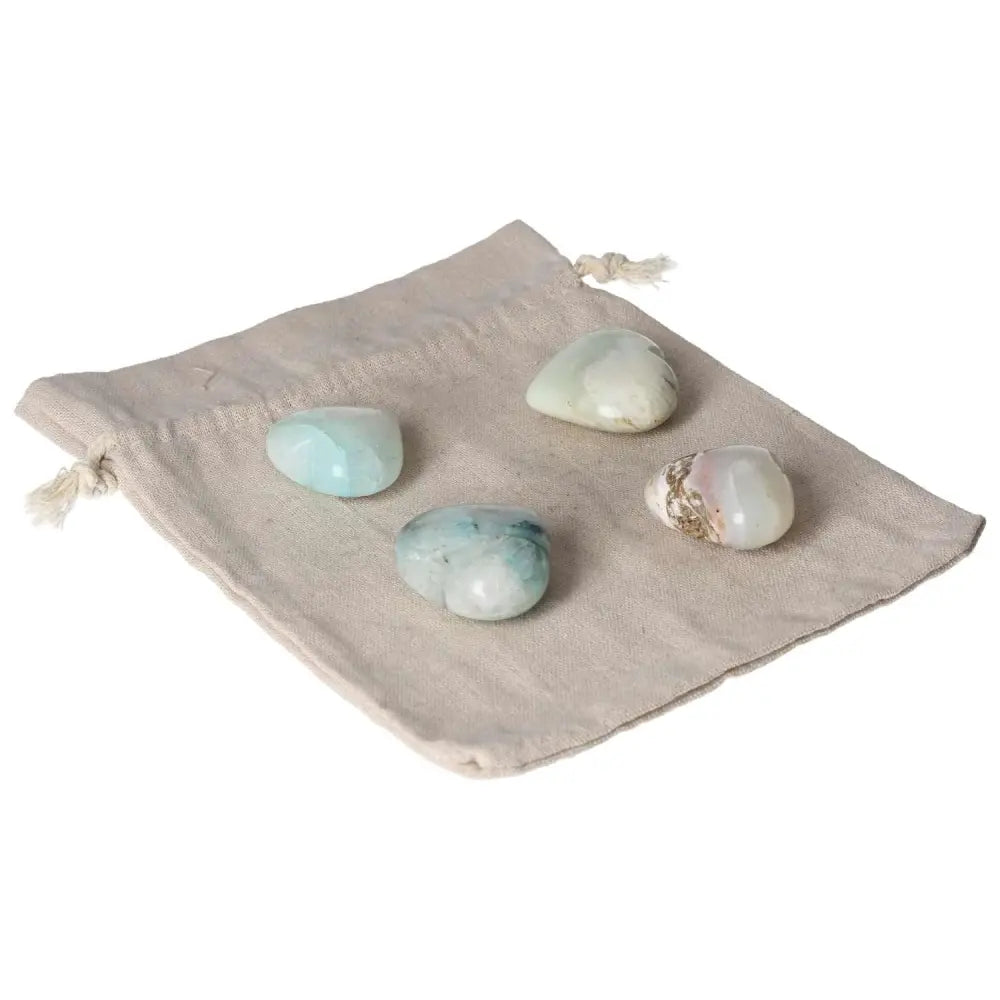 Four chrysocolla stones on a drawstring pouch, symbolizing clarity in speech and enhanced feminine energy.
