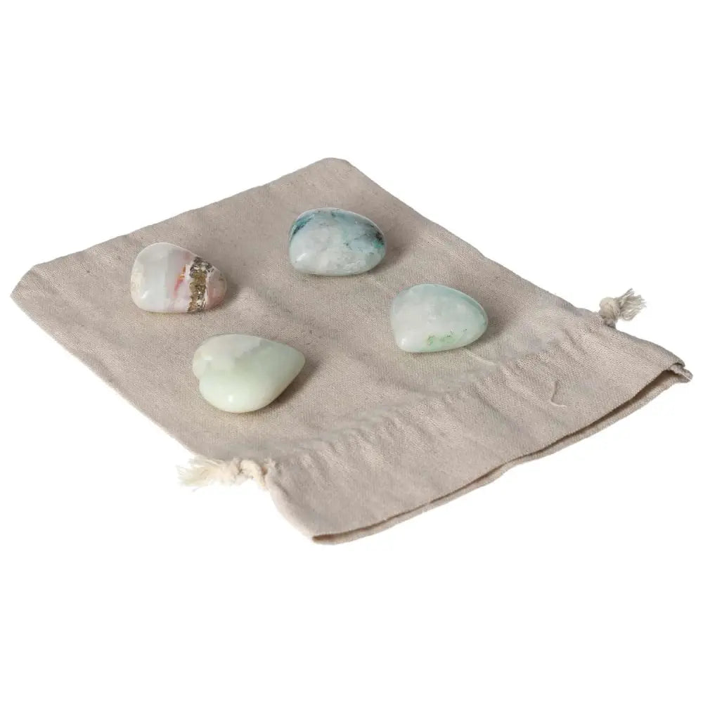 Four chrysocolla heart stones on a cloth pouch, showcasing powerful feminine energy and communication enhancing properties.