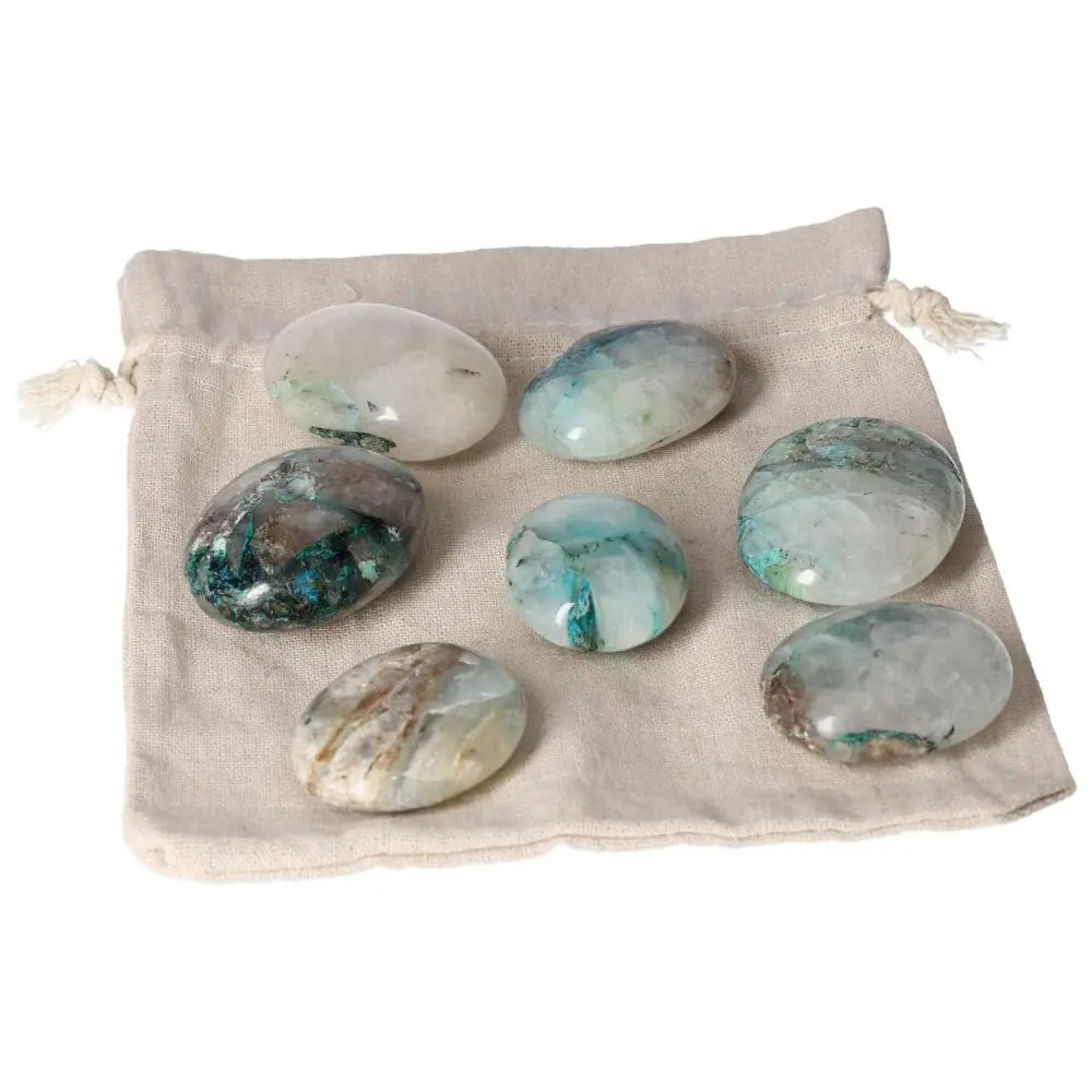 Set of chrysocolla palmstones on a drawstring cloth bag, showcasing their blue and green hues, known for enhancing communication and intuition.