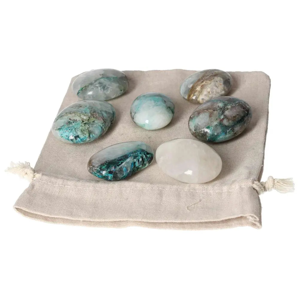 Collection of Chrysocolla palmstones on a beige drawstring bag, showcasing their vibrant colors and soothing energy.