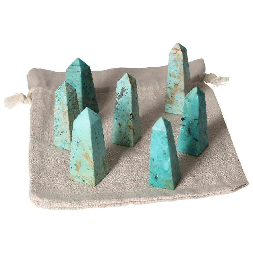 Chrysocolla tower set on beige pouch, showcasing vibrant turquoise hues and strong feminine energy for improved communication and emotions.
