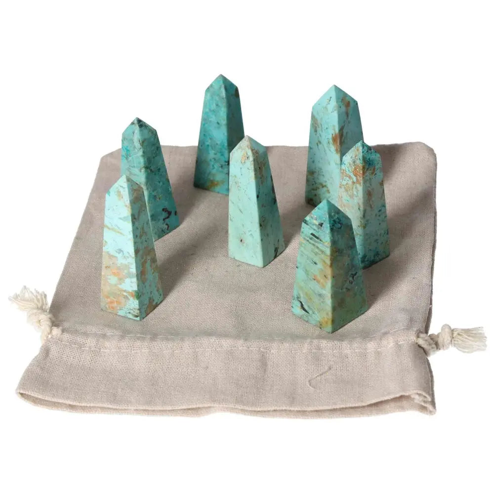 A set of chrysocolla towers on a beige cloth, known for enhancing communication skills and feminine energy benefits.