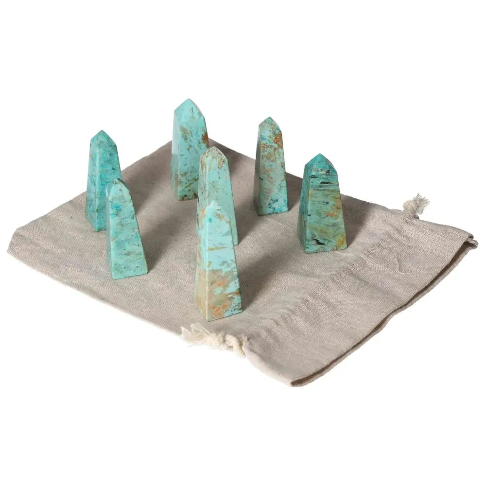 Chrysocolla towers on a cloth mat, showcasing their vibrant blue-green hues, known for enhancing communication and feminine energy.
