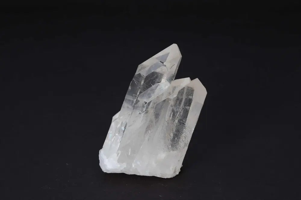Clear Quartz Cluster radiating pure energy with multiple crystal points against a dark background.