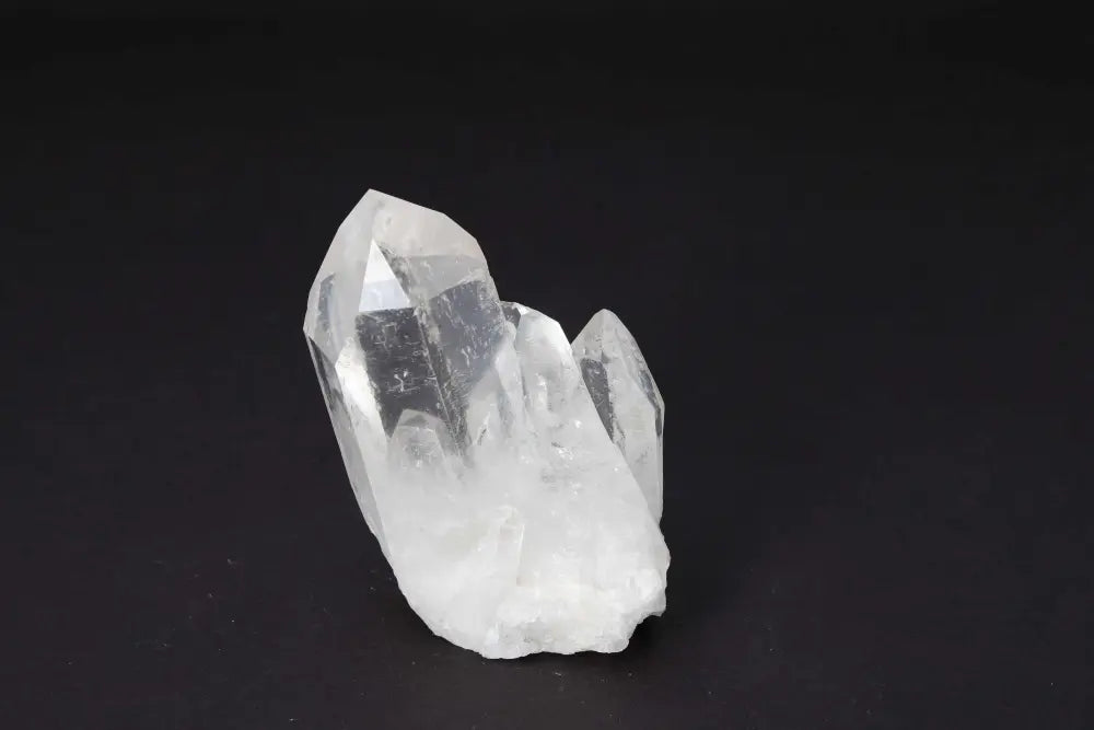 Clear Quartz Cluster emitting radiant clarity and high vibrational energy on a dark background.