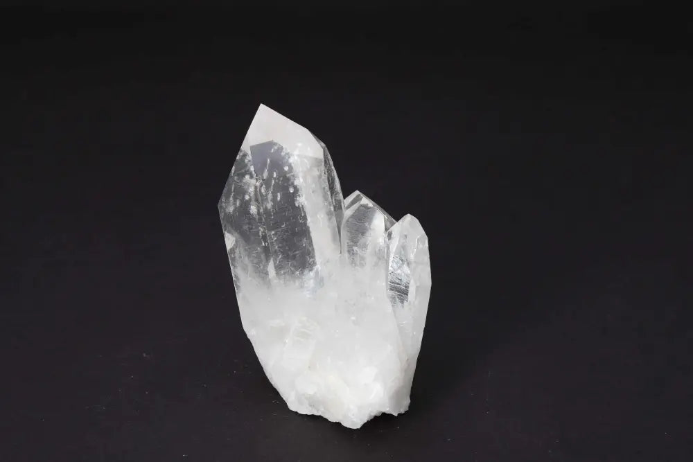 Clear Quartz Cluster on dark background, showcasing natural crystal points and high vibrational energy amplification properties.