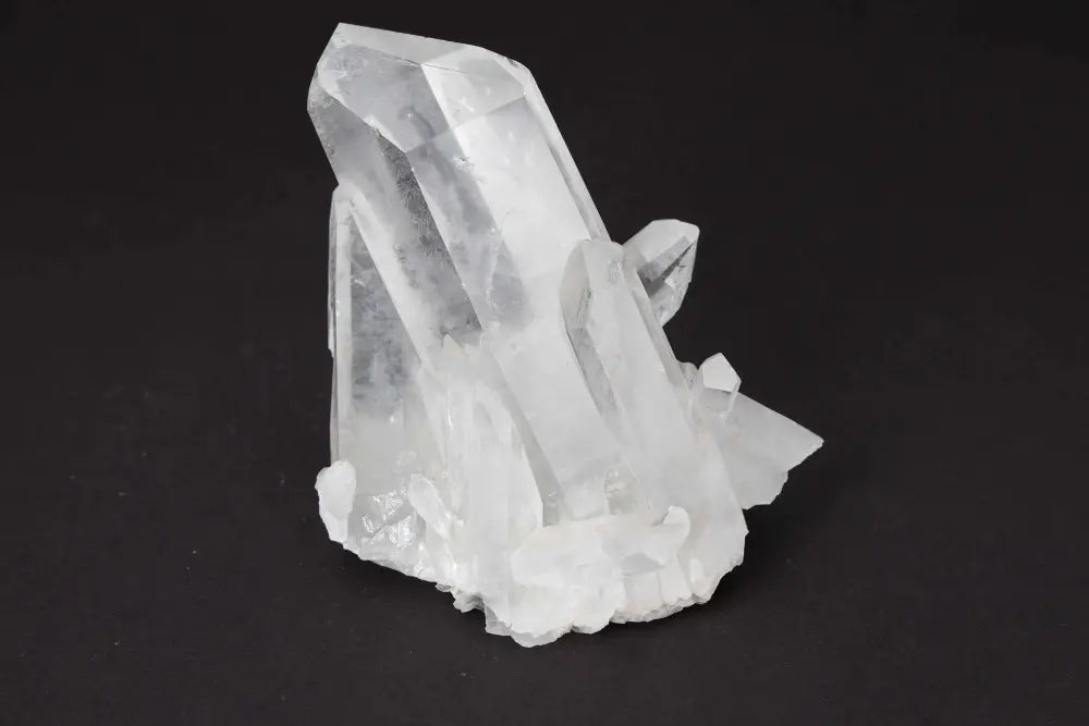 Clear Quartz Cluster on dark background, showcasing natural crystal points and amplifying pure energy and vibrational clarity.