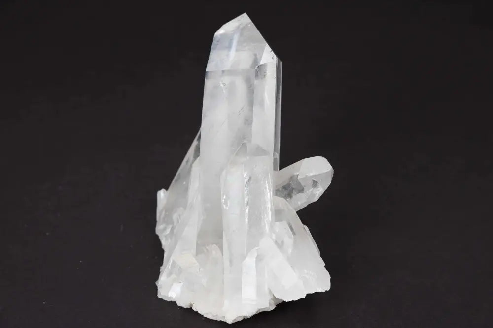 Clear Quartz Cluster with multiple crystal points, amplifying energy and purity against a dark background.