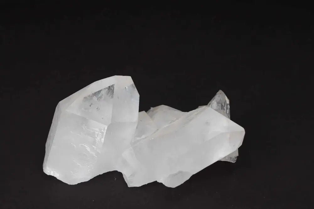 Clear quartz cluster on dark background, showcasing multiple crystal points forming a natural formation for energy amplification and purification.