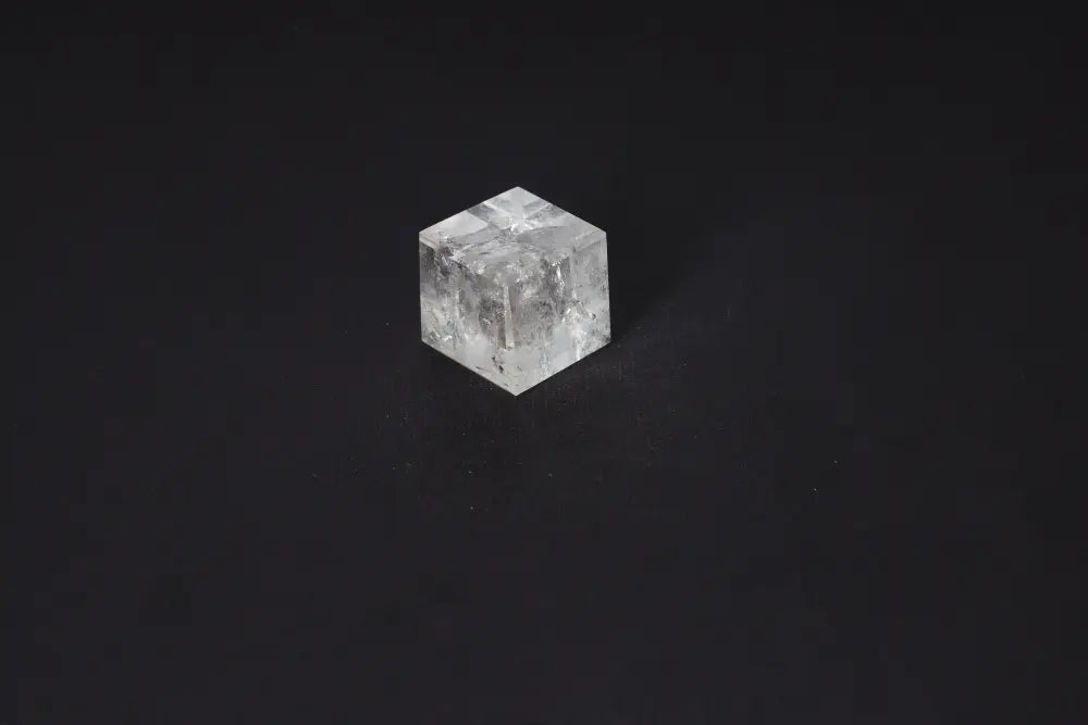 Clear Quartz Cube 3.5 cm on black background, known for purification and neutralizing negative vibrations and electromagnetic radiation.