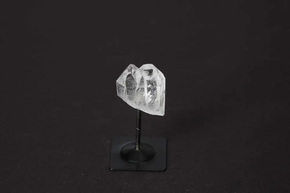 Clear quartz crystal on a metal stand, highlighting its healing properties and connection to chakras and zodiac signs.