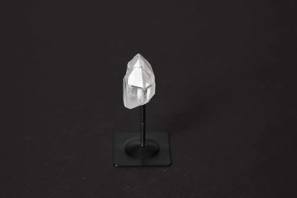 Clear quartz crystal on a sleek metal stand, symbolizing energy and balance, enhances chakra and zodiac support.