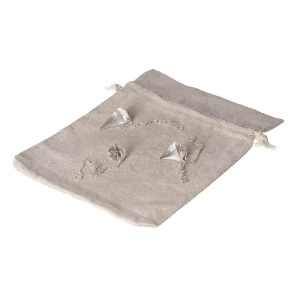 Clear Quartz pendulum set on a beige pouch, ideal for purification and harmonizing energy.