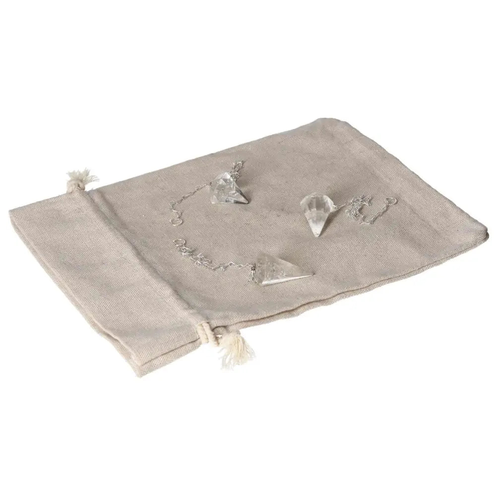 Clear Quartz Pendulum on a beige cloth, ideal for purification and energy harmonization. Absorbs negative vibrations and electromagnetic radiation.