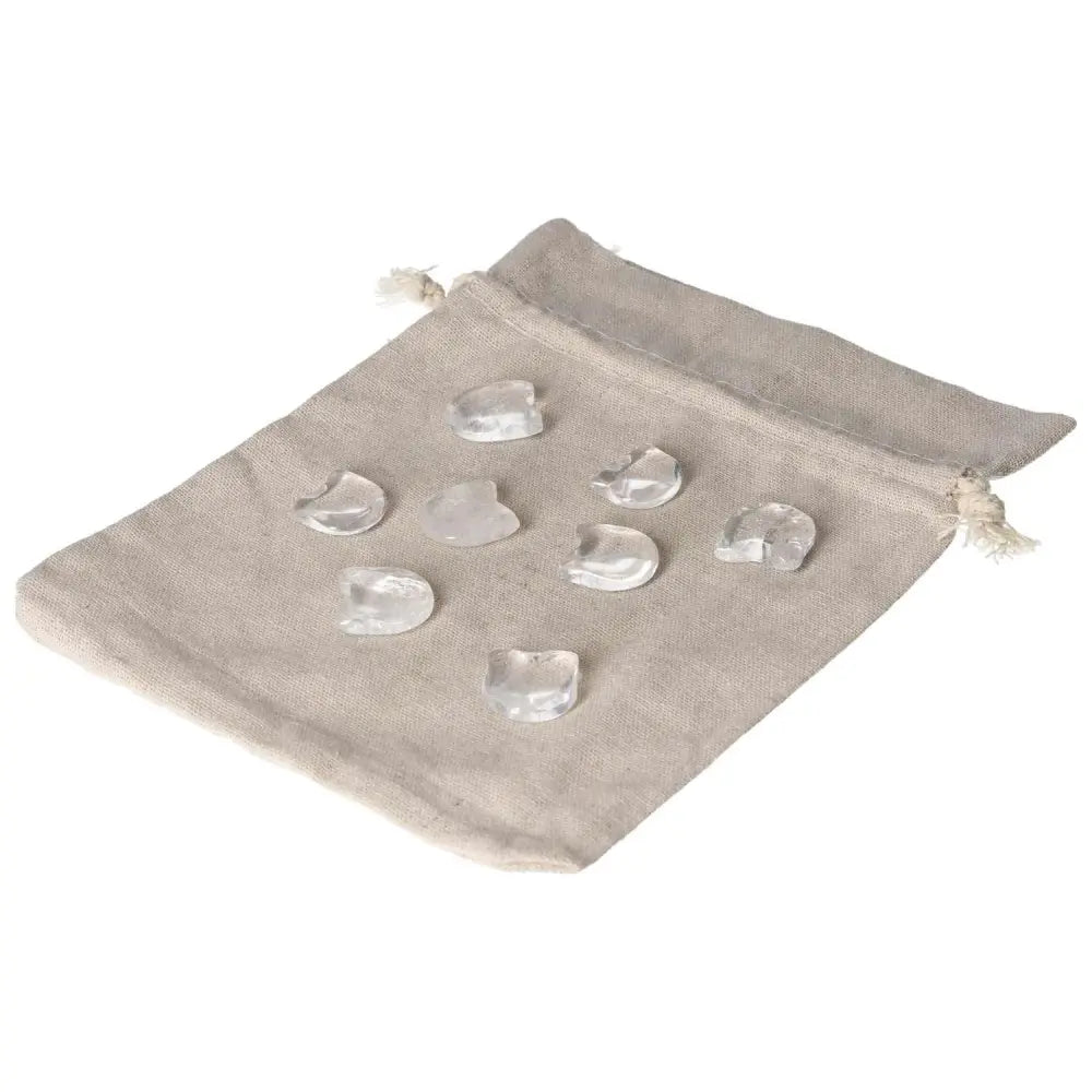 Nine small clear quartz cat carvings displayed on a beige cloth bag, symbolizing clarity and playful energy in spiritual practice.