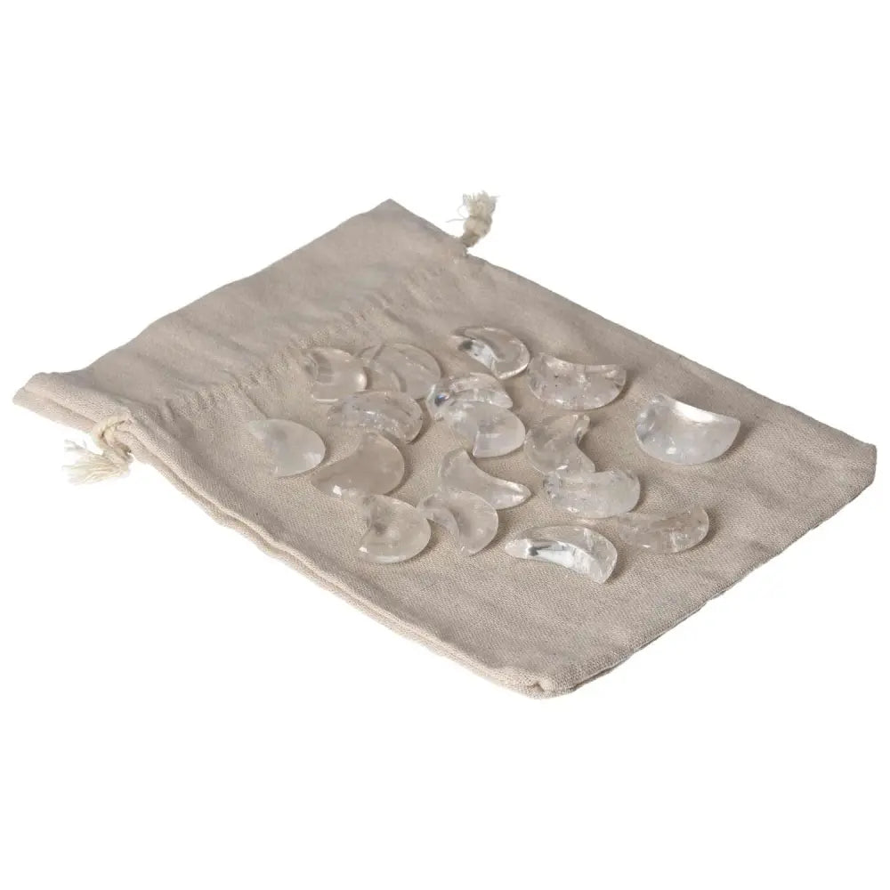 Clear Quartz Small Moon stones on a beige drawstring pouch, known for their purification and harmonizing properties.