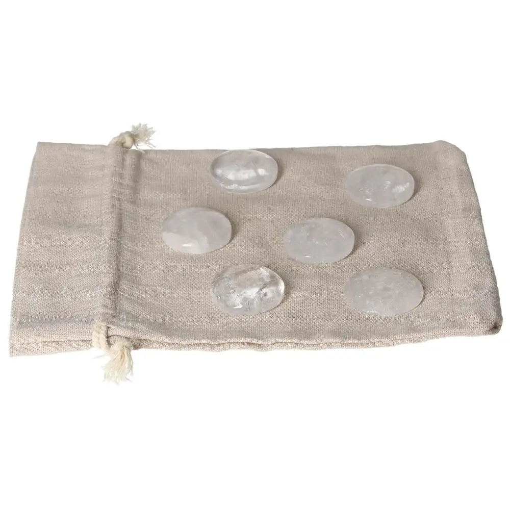 Clear Quartz small palmstones on a beige drawstring bag, ideal for purification and neutralizing negative energy and electromagnetic radiation.