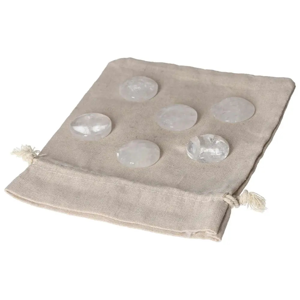 Set of clear quartz small palmstones on a beige linen pouch, ideal for purification and balancing energy.