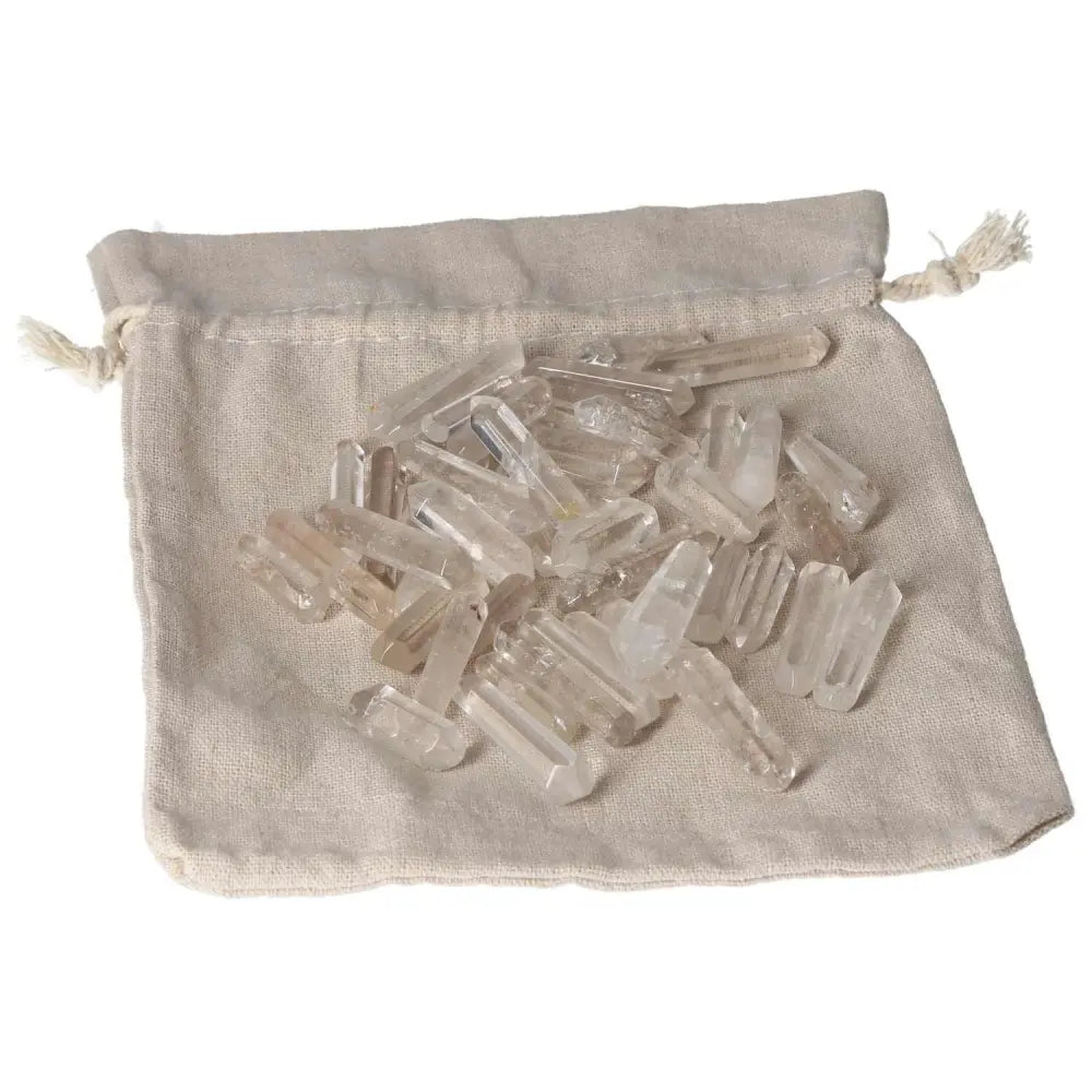 Small clear quartz sticks on a beige fabric pouch, known for purification and neutralizing negative energy and electromagnetic radiation.