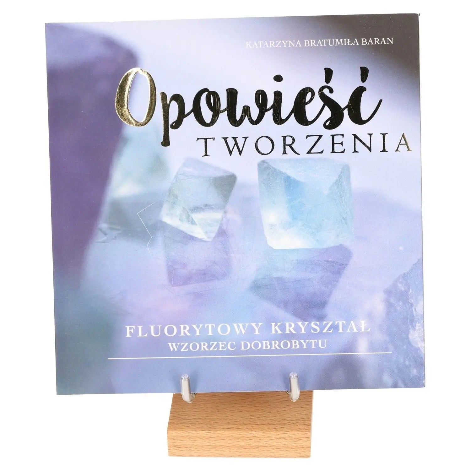 Cover of a book titled 'Opowieść Tworzenia' with images of fluorite crystals on a wooden stand.