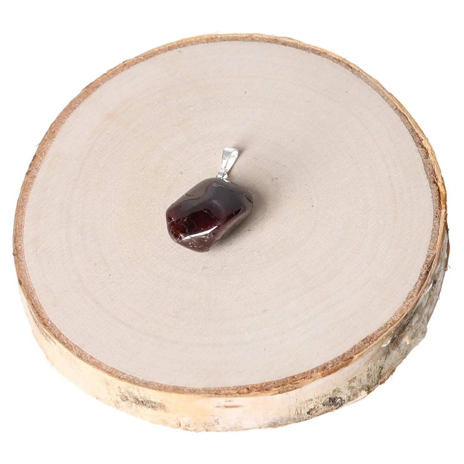 Garnet AA Tumbled Pendant with deep red hue on wooden platform, showcasing smooth texture and radiant energy.