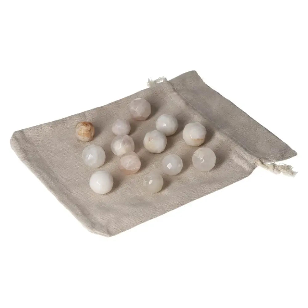 A collection of small geometric spheres made of Golden Healer crystal, displayed on a beige fabric pouch for healing and decoration.