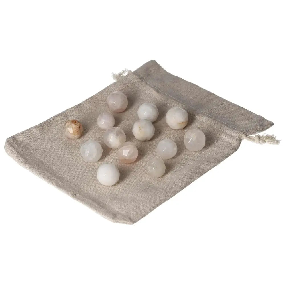 Collection of small geometric gemstone spheres displayed on a beige cloth pouch.