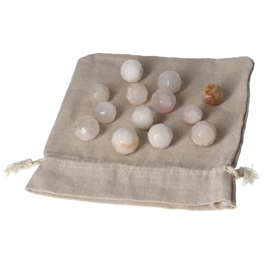 Small geometric spheres on a natural fabric bag, showcasing polished stones with varying hues, perfect for holistic and decorative use.