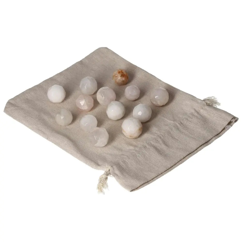 Mixed quartz geometric spheres on a beige cloth bag, featuring a variety of white, clear, and amber tones for decorative or healing purposes.