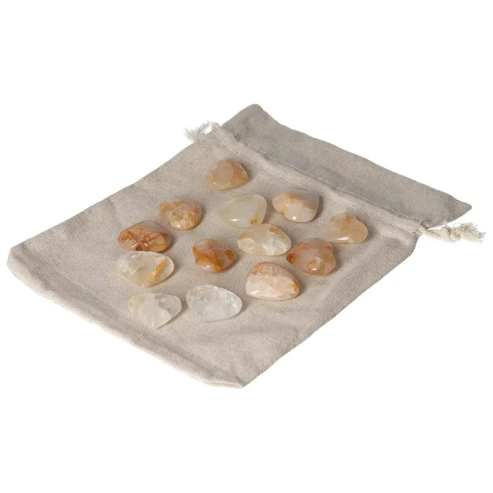 Golden Healer small heart stones laid on a beige pouch, showcasing their natural hues and polished finish.