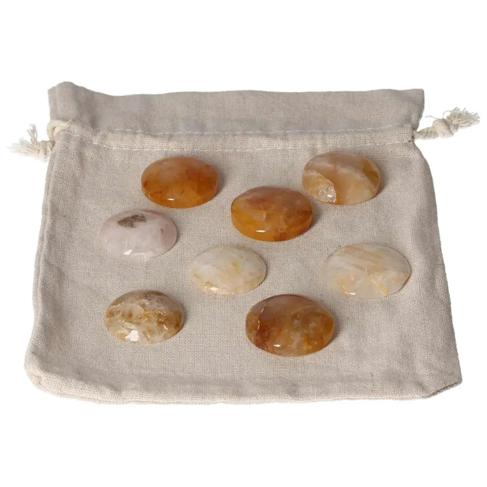 Golden Healer small palmstones displayed on a beige drawstring pouch, featuring warm golden and cream tones, ideal for holistic healing practices.