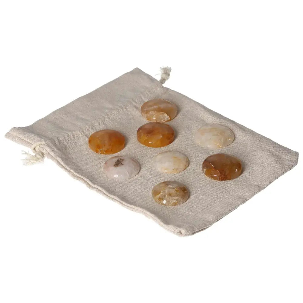 Collection of golden healer small palmstones displayed on a beige cloth bag