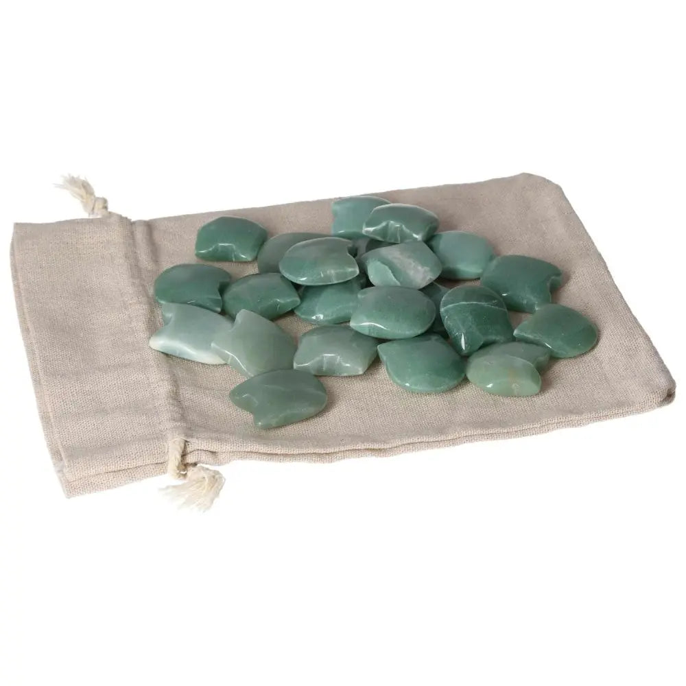 Green Aventurine stones scattered on a beige cloth bag, promoting luck, prosperity, and inner peace with their calming properties.