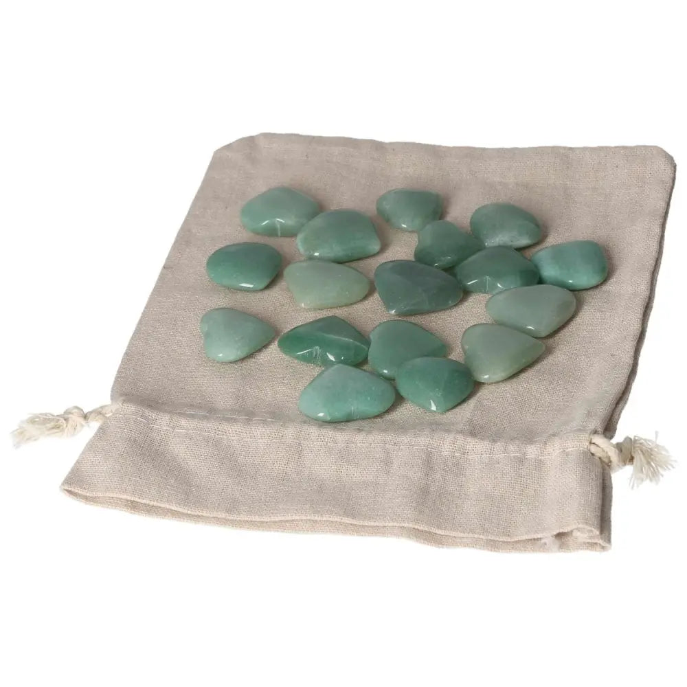 A collection of small Green Aventurine heart-shaped stones placed on a beige cloth pouch. Ideal for attracting luck and promoting inner peace.
