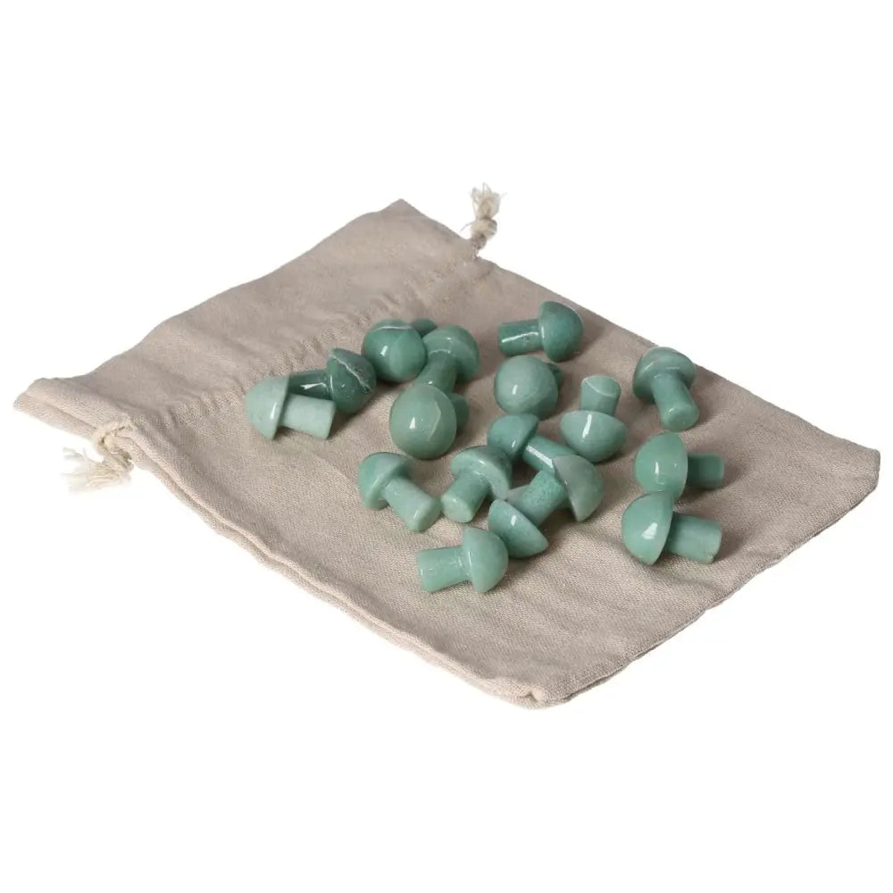 Small Green Aventurine mushroom stones on a beige cloth, known for boosting self-confidence and attracting luck and prosperity.