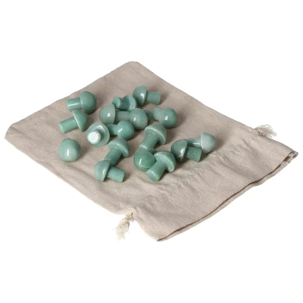 Collection of small green aventurine mushroom stones on a beige cloth, symbolizing luck, prosperity, and calmness.