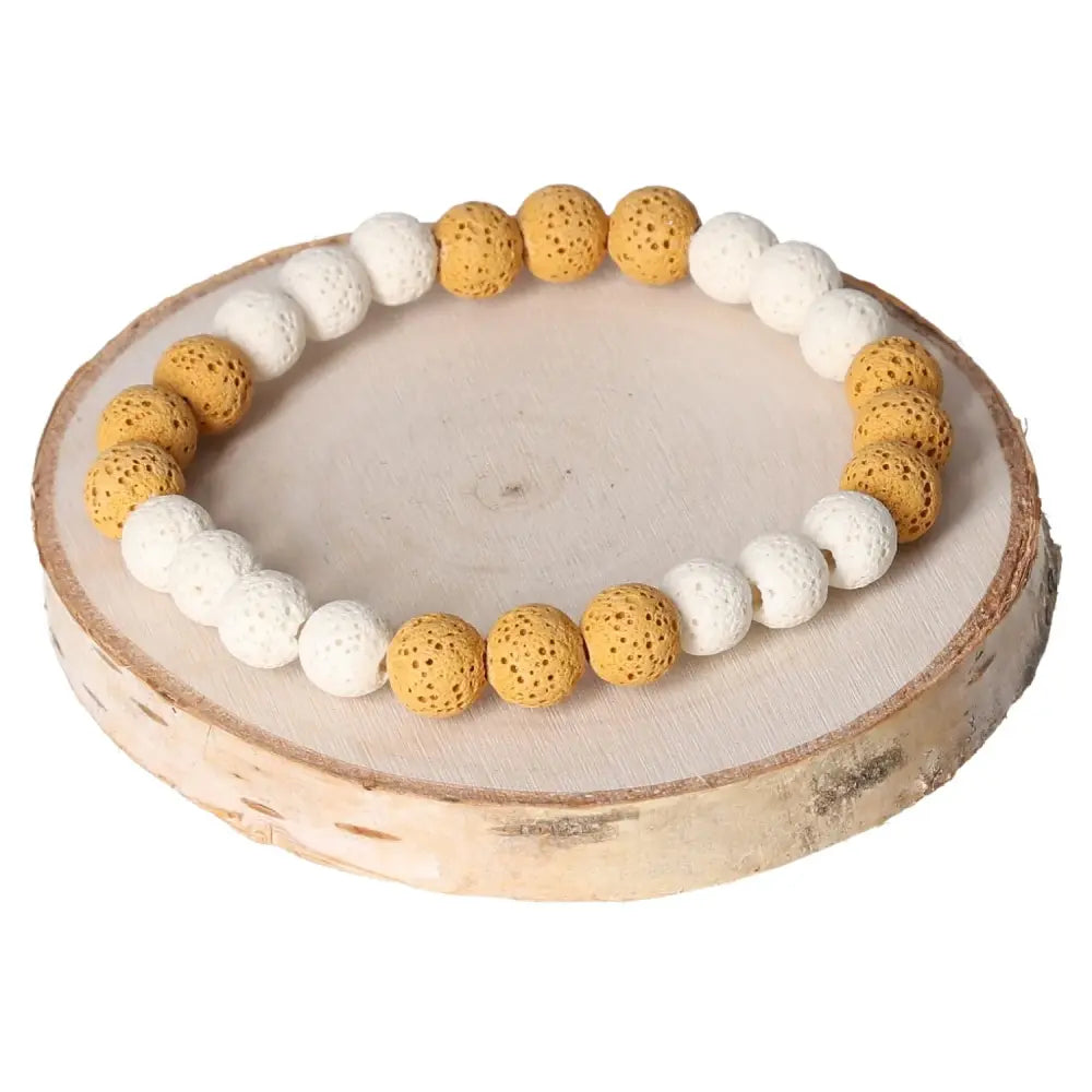 Lava Bracelet 8mm featuring white and yellow volcanic stone beads, displayed on a round wooden platform, highlighting its earthy elegance.