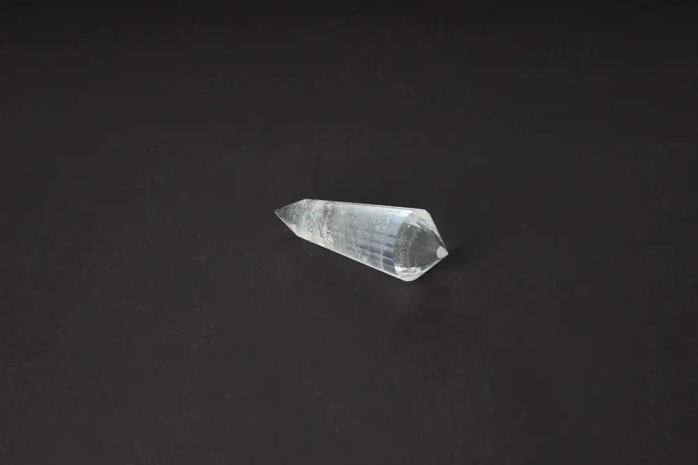 Lemurian Quartz Point with striations, embodying ancient wisdom and energies, isolated on a dark background.