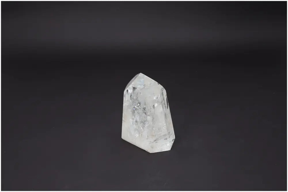 Elegant Lemurian Quartz Obelisk from Sylvia Crystals, symbolizing purity and spiritual enhancement on a dark background.