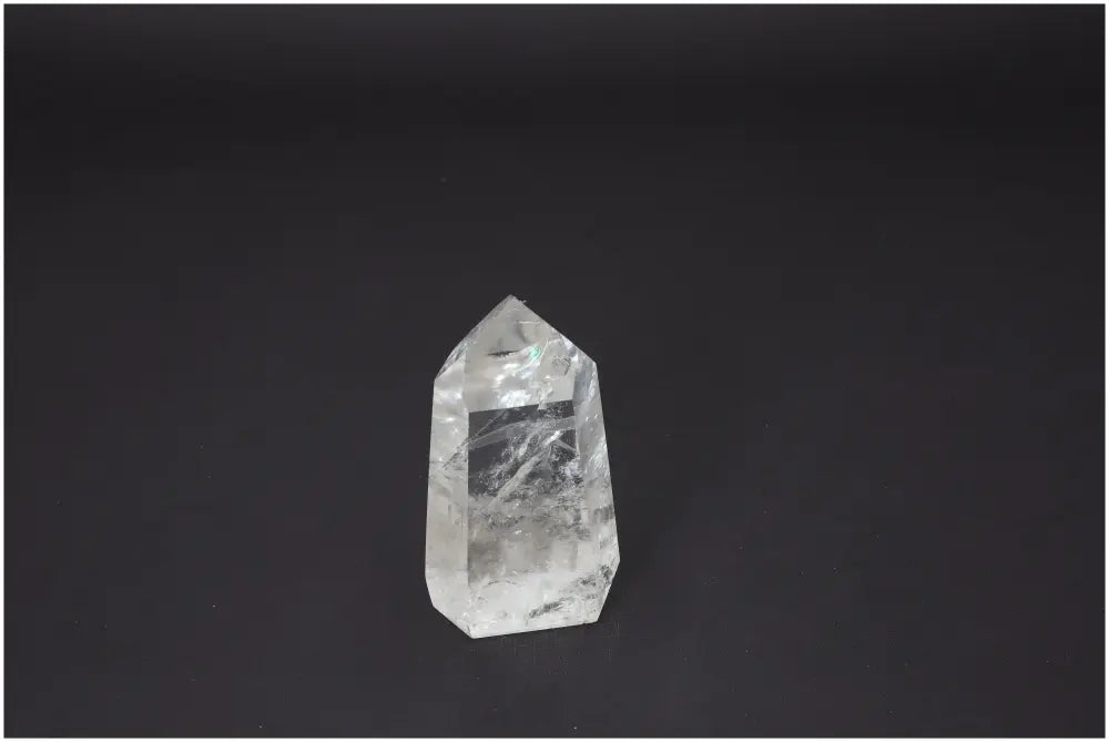 Clear Lemurian Quartz Obelisk against black background, known for chakra balancing and spiritual energy qualities.