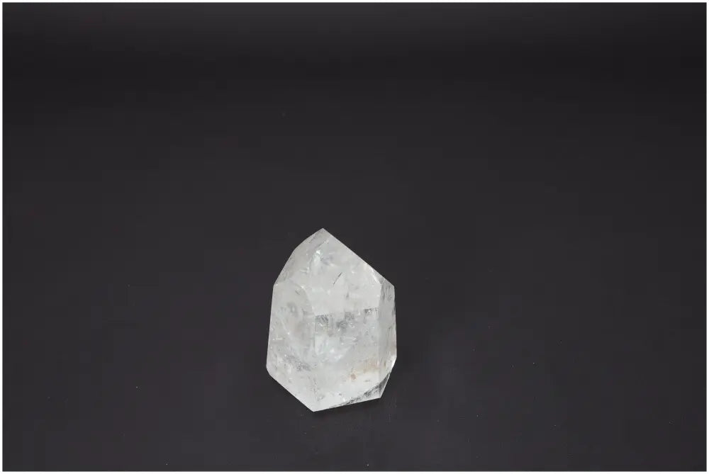 Lemurian Quartz Obelisk with healing properties for chakras and zodiacs, clear crystal against dark background.