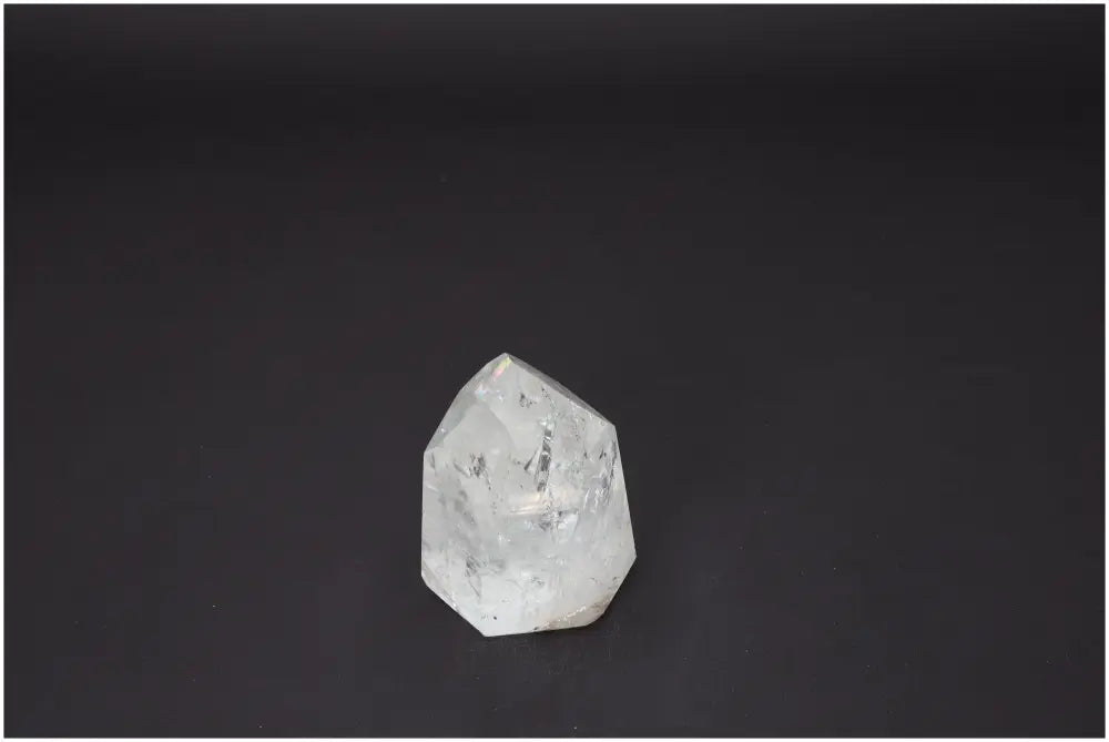 Lemurian Quartz Obelisk against dark background, showcasing its clear, shimmering properties and spiritual significance.