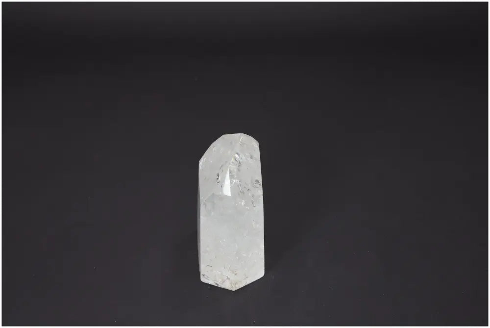 Clear Lemurian Quartz Obelisk on dark background, known for its spiritual energy, chakra alignment, and unique quartz properties.