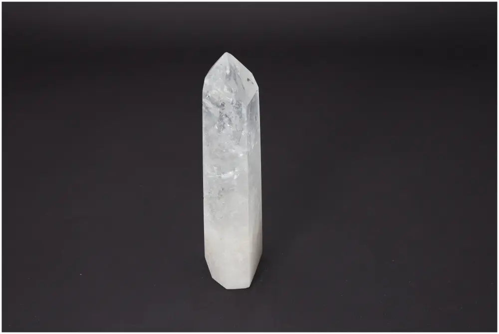 Clear Lemurian Quartz Obelisk with spiritual and chakra balancing properties against a dark background.