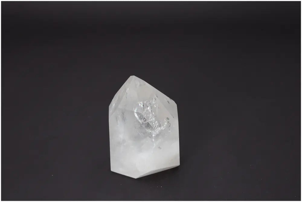 Clear Lemurian Quartz Obelisk on a dark background, showcasing its unique crystal clarity and spiritual significance.