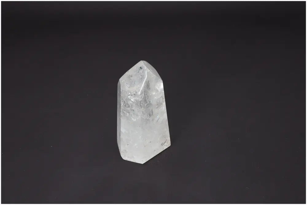 Lemurian Quartz Obelisk for chakras and zodiac, clear quartz crystal with energetic and spiritual properties against black background.