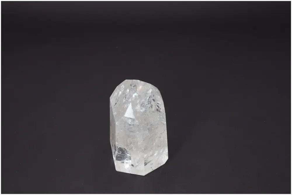 Lemurian Quartz Obelisk on black background, reflecting light, known for its spiritual properties and chakra alignment benefits.
