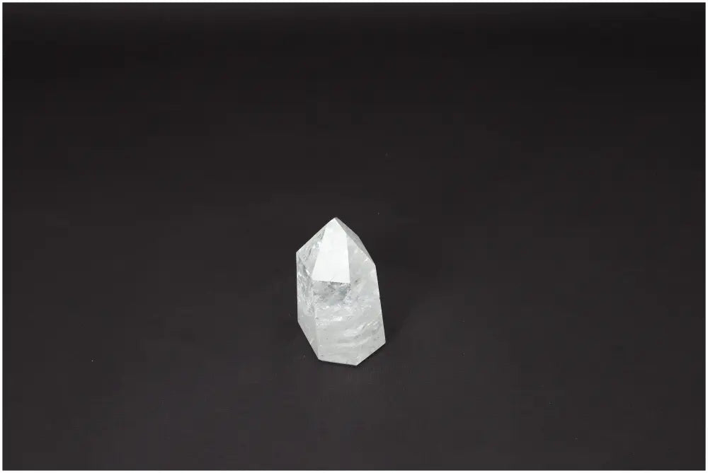 Clear Lemurian Quartz Obelisk on black background, known for its spiritual properties and chakra alignment.