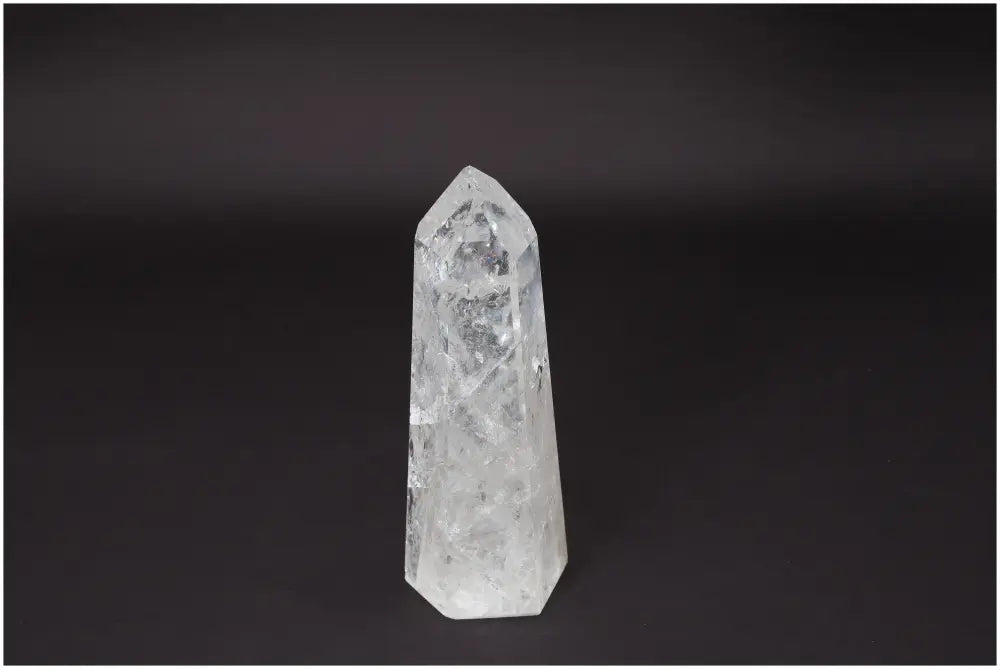 Lemurian Quartz Obelisk, clear crystal, amplifies energy, enhances clarity and balance, ethically sourced, on a dark background.