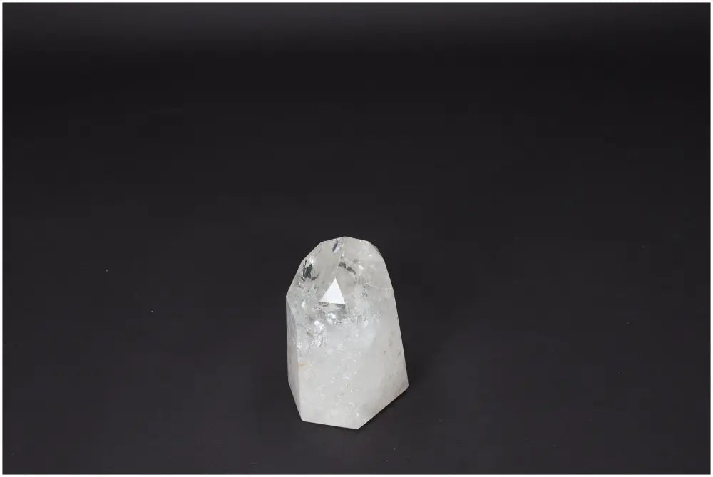 Lemurian Quartz Obelisk on dark background, clear crystal known as Master Healer, promotes clarity and personal growth.
